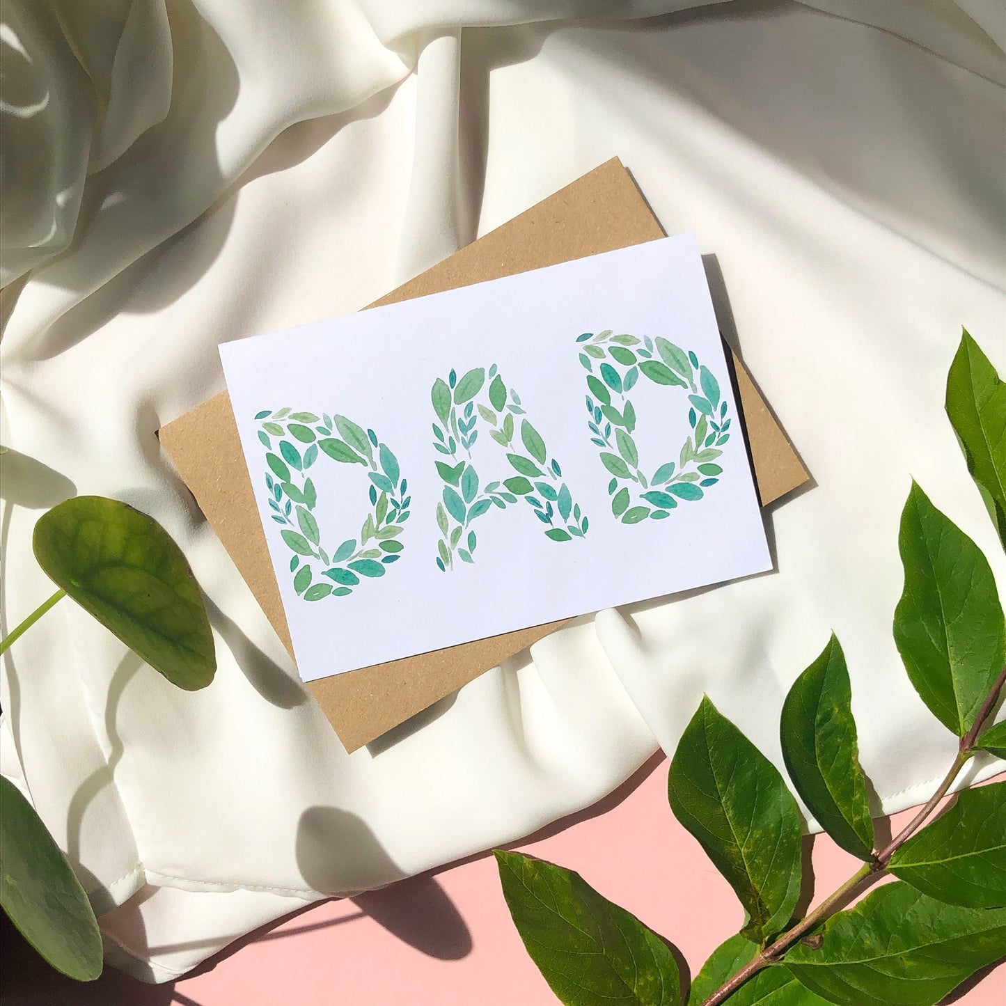 A Father's Day card with the word "DAD" spelled out beautifully in green leaves of various shades and shapes. The card offers a simple yet elegant way to show appreciation and affection for a beloved dad on his special day.