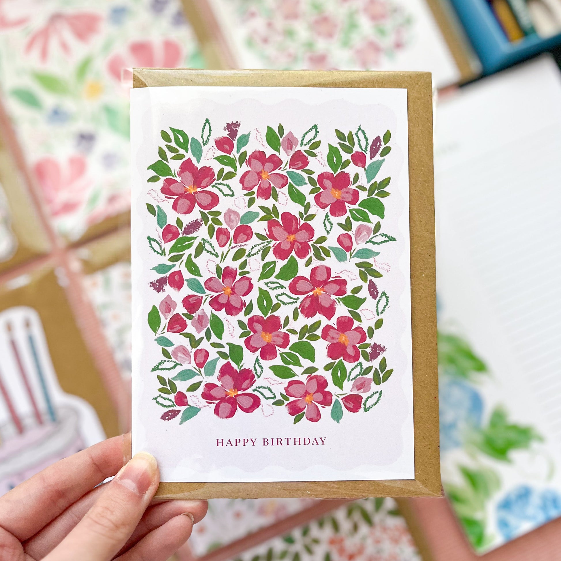 Floral birthday card held by a hand with more cards in the background