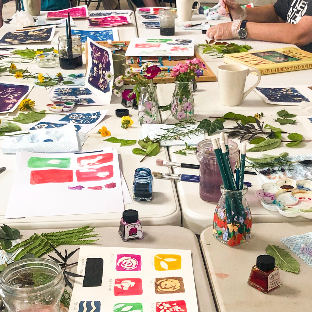 Artistic workspace with paint samples, brushes, and ink bottles on a table.
