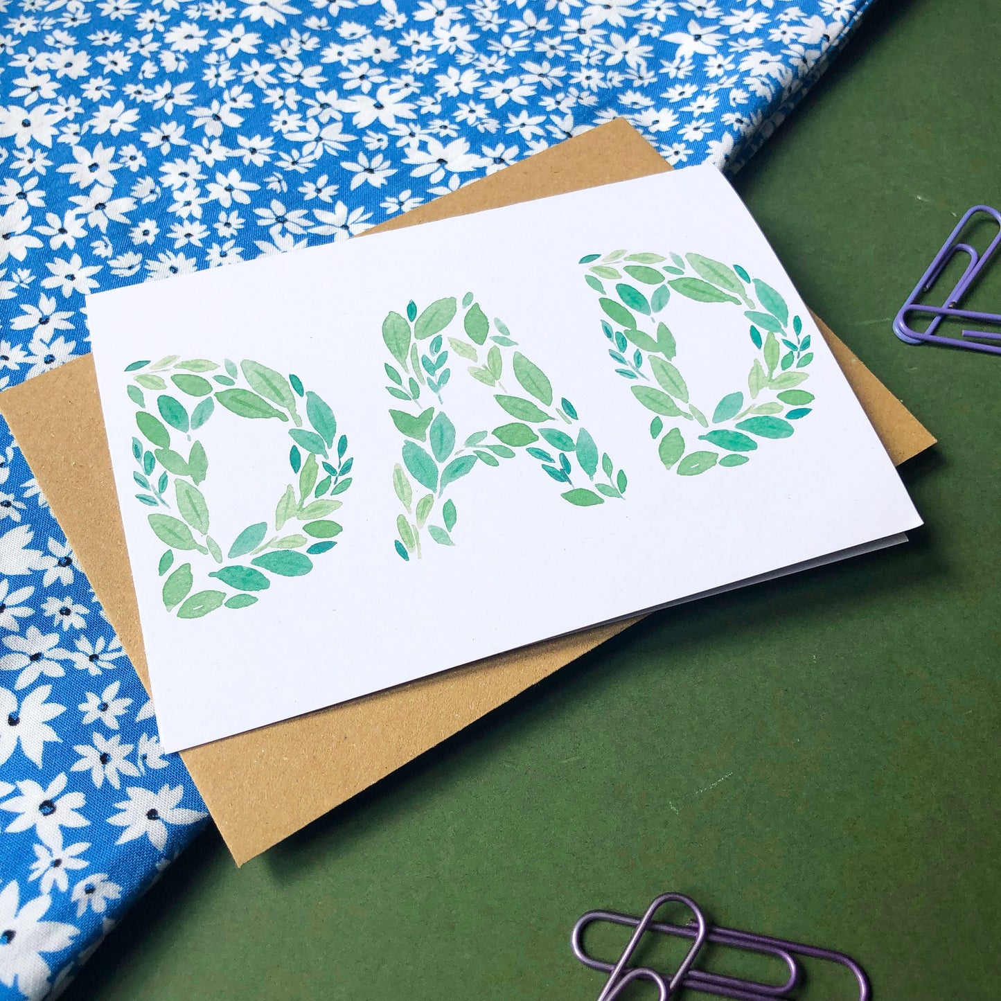 A Father's Day card with the word "DAD" spelled out beautifully in green leaves of various shades and shapes. The card offers a simple yet elegant way to show appreciation and affection for a beloved dad on his special day.
